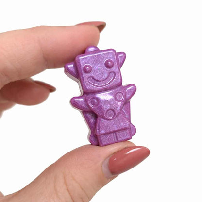 Hand holding a small pink robot toy against a white background