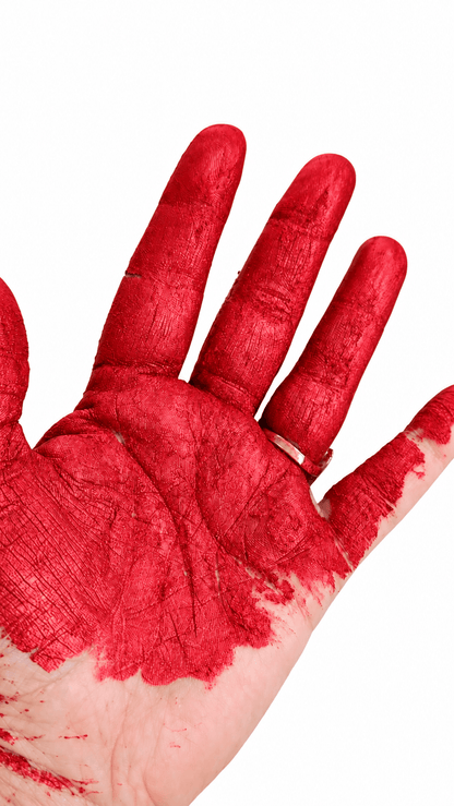 A close-up of a human hand with the fingers and palm covered in thick, textured red paint or pigment against a plain white background.