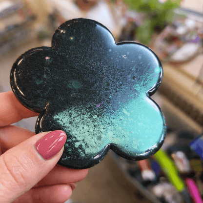Glossy resin flower showcasing green interference pigment with colour-shift shimmer, photographed in natural light.