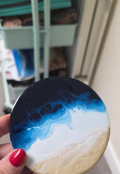 Coaster with blue and white design held by a hand with red nail polish.