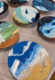 Set of resin coasters with artistic blue and green designs on a wooden surface