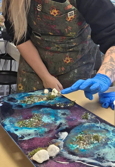 Person working on a resin art project with a colorful background